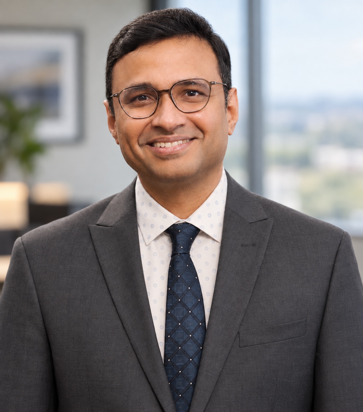 Dr. Sachin Arakere Nataraj smiling in a charcoal suit and glasses